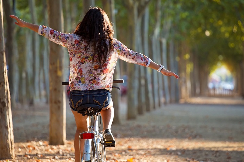 Outdoor portrait of pretty young girl riding bike in a forest.